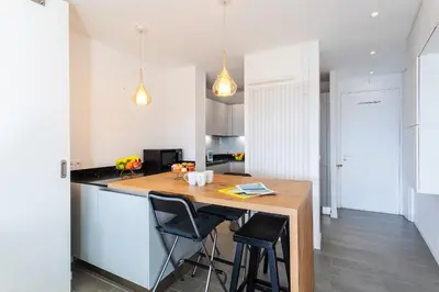 a kitchen with a wooden table and two chairs at Esterel AP4431 By Riviera Holiday Homes in Villefranche-sur-Mer