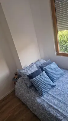 a bed with blue pillows in a bedroom with a window at Ete Nice in Nice