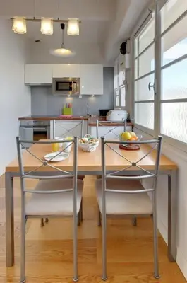 a kitchen with a wooden table with chairs and a dining room at MyrAzur Carre d'Or in Nice