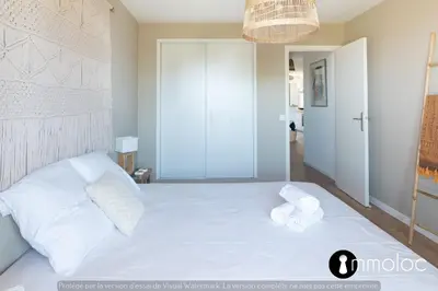 a bedroom with a white bed with towels on it at Air-conditioned apartment facing the port of Saint Laurent with 2 bedrooms in Saint-Laurent-du-Var
