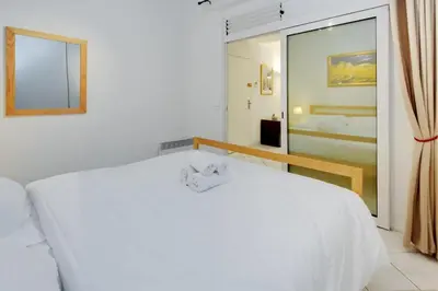 a white bedroom with two beds and a window at Rue St Gaetan location old town in Nice