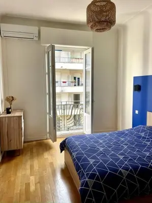 a bedroom with a blue bed and a balcony at Appartement Niçois in Nice