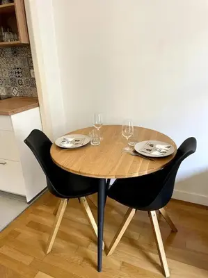 a wooden table with two chairs and wine glasses at Appartement Niçois in Nice