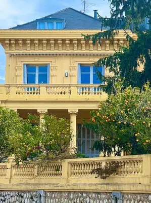 a large yellow building with a balcony and trees at Appartement exceptionnel belle époque avec grande terrasse plein sud in Nice
