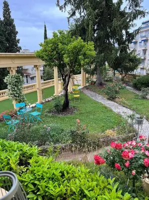 a garden with chairs and flowers and a bridge at Appartement exceptionnel belle époque avec grande terrasse plein sud in Nice