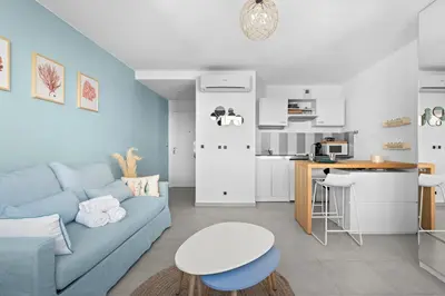 a living room with a blue couch and a kitchen at Studio Amanda - Welkeys in Nice
