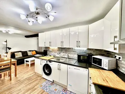 a kitchen with white cabinets and a living room at ApartHotel Riviera - ANGLE DROITE - Old town Promenade des Anglais in Nice
