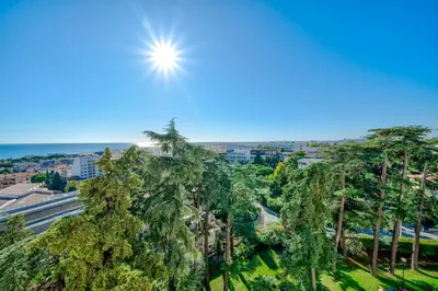 a sun shining over a city with palm trees at Superbe 3p vue mer avec parking in Nice