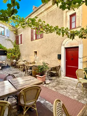a patio with tables and chairs and a red door at Évasion Authentique à Èze, avec vue Mer in Èze