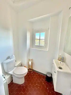 a bathroom with a toilet and a sink and a window at Évasion Authentique à Èze, avec vue Mer in Èze