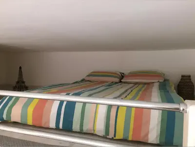 a bed with striped sheets and two pillows on it at Studio Nice Centre 4P Jean médécin avenue in Nice