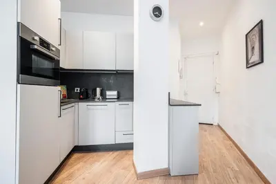 a white kitchen with white cabinets and a wooden floor at 1 GAUTIER 101 - Joli studio equipe - Quartier du Port in Nice