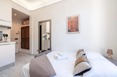a white bed in a room with a kitchen at 1 GAUTIER 501 - Studio boheme - Quartier du port in Nice