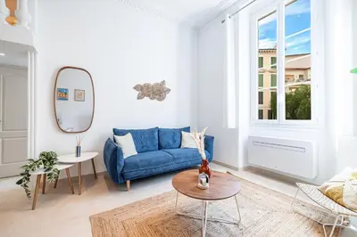 a living room with a blue couch and a mirror at 1 LONGCHAMP - Joli appartement - Carre d Or - Climatise in Nice