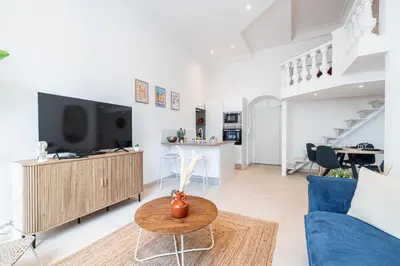 a living room with a tv and a blue couch at 1 LONGCHAMP - Joli appartement - Carre d Or - Climatise in Nice