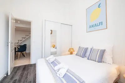 a white bedroom with a large bed with blue pillows at 1 LONGCHAMP - Joli appartement - Carre d Or - Climatise in Nice