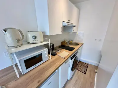 a small kitchen with white cabinets and a microwave at L'Éclat Safran - Royal Luxembourg in Nice