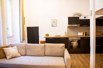 a white couch in a living room with a kitchen at Appartement La Mezzanine in Nice