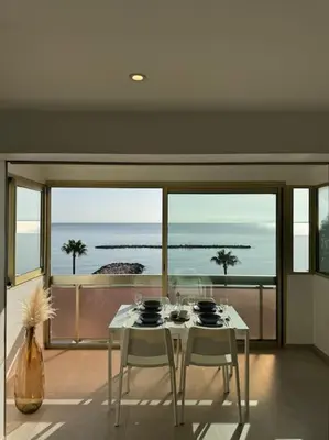 a dining room with a table and chairs and a view of the ocean at Évasion Mer & Vue Imprenable in Saint-Laurent-du-Var