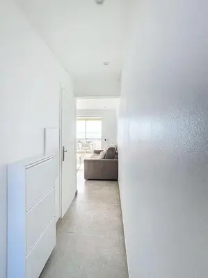 a white hallway with a couch in a room at Évasion Mer & Vue Imprenable in Saint-Laurent-du-Var