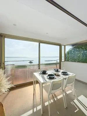 a white table and chairs in a room with a large window at Évasion Mer & Vue Imprenable in Saint-Laurent-du-Var