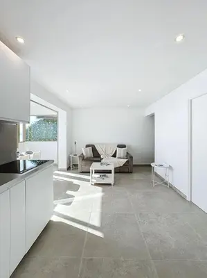 a white kitchen and living room with a couch at Évasion Mer & Vue Imprenable in Saint-Laurent-du-Var