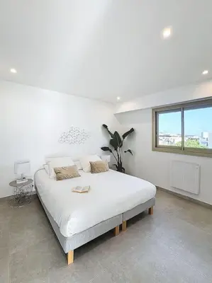 a white bedroom with a large bed in a room at Évasion Mer & Vue Imprenable in Saint-Laurent-du-Var