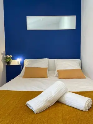 a bedroom with a blue wall and a white bed at Le Village - cosy flat 5 min walk away from sea in Nice