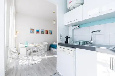 a kitchen with white cabinets and a table with chairs at 37 LAMARTINE - Magnifique Studio Art Deco - Centre-ville in Nice