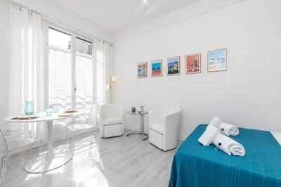 a white room with a bed and a table at 37 LAMARTINE - Magnifique Studio Art Deco - Centre-ville in Nice