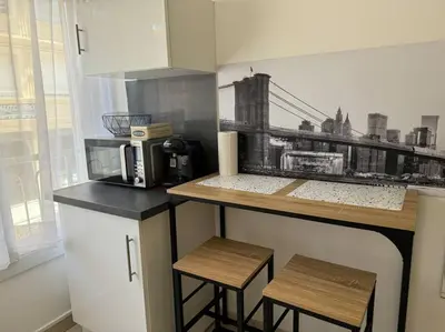 a kitchen with a counter with a microwave and stools at Studio lumineux in Nice