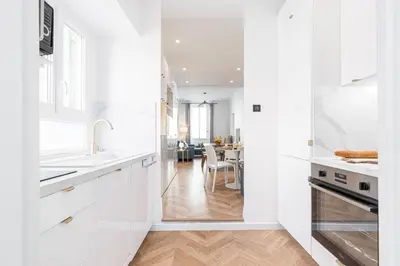a white kitchen with white cabinets and a dining room at 37 MASSENA LOT 2 - Superbe 3 pieces - Zone Pietonne - A-C in Nice