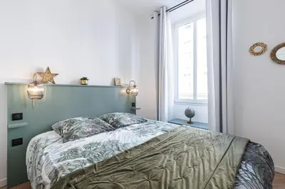 a bedroom with a bed with a blue headboard and a window at 37 MASSENA LOT 2 - Superbe 3 pieces - Zone Pietonne - A-C in Nice