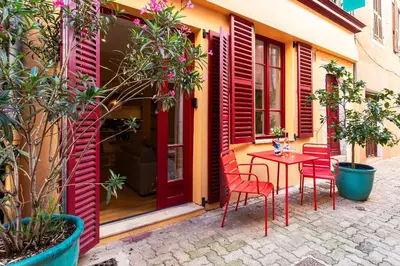 a patio with red doors and a table and chairs at COSY VOLTI AP4434 By Riviera Holiday Homes in Villefranche-sur-Mer