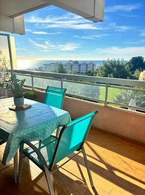 a table and chairs on a balcony with a view at Appartement lumineux Vue Mer, Piscine et tennis in Nice