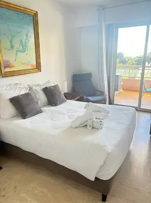a bedroom with a large white bed with a window at Appartement lumineux Vue Mer, Piscine et tennis in Nice