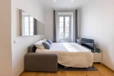 a bedroom with a bed and a chair and a mirror at Le Carré d'Or - à 2 min à pied du centre-ville in Nice