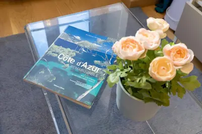 a book and a vase with roses on a table at Le Carré d'Or - à 2 min à pied du centre-ville in Nice