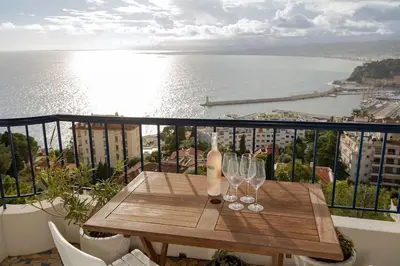 a wooden table with wine glasses on a balcony at Magnifique appartement vue mer Mont Borron in Nice