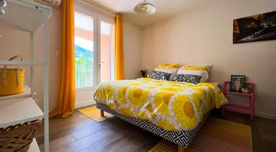 a bedroom with a bed with a yellow comforter and a window at Maison LeFleur in Falicon