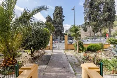 a garden with palm trees and a fence at Appartement 2 chambres à 15 mn de la mer in Nice