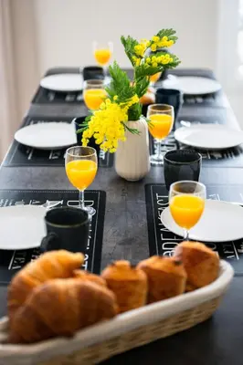 a table with a plate of bread and glasses of orange juice at La Galerie 58 - Luxe & Design en centre ville in Nice