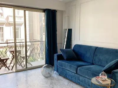 a living room with a blue couch and a balcony at Studio Carré Or - Centre Nice 2m à pied de la mer in Nice