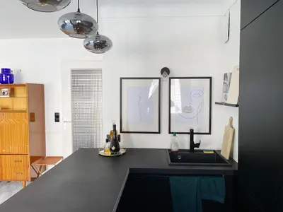 a kitchen with a black counter top with two pictures on the wall at Studio Carré Or - Centre Nice 2m à pied de la mer in Nice