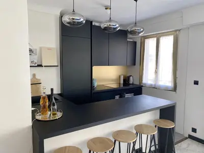 a kitchen with a black counter and some stools at Studio Carré Or - Centre Nice 2m à pied de la mer in Nice