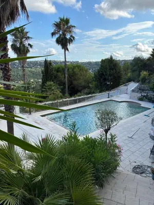 a swimming pool with palm trees in the background at Villa Gloria Nouvel Hôte in Saint-Jeannet