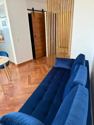 a blue couch in a living room with a wooden floor at Elégant studio de 25m2 in Saint-Laurent-du-Var