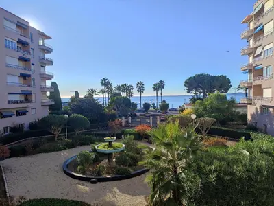 a garden with a fountain and palm trees in front of a building at Studio vue mer in Cagnes-sur-Mer
