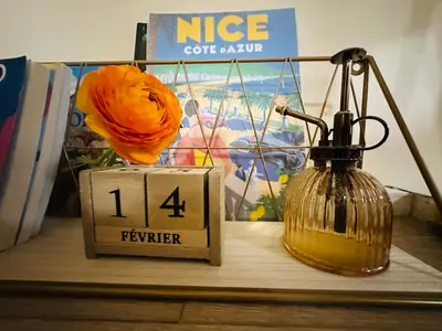 a clock with a flower and a vase on a table at Amber Apartment Nice - Central Highlights and Beach in Nice