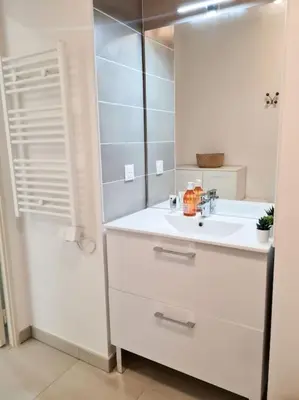 a white bathroom with a sink and a mirror at Magnifique Appartement - Parking privé - Nice in Nice